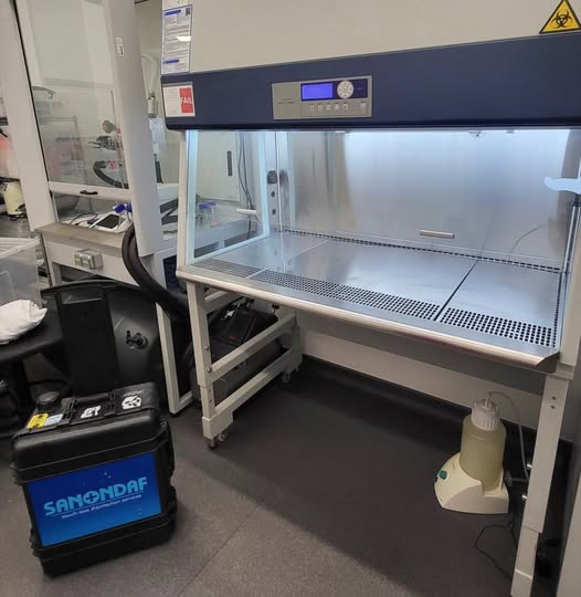 Sanondaf unit positioned beside an open biosafety cabinet in a laboratory